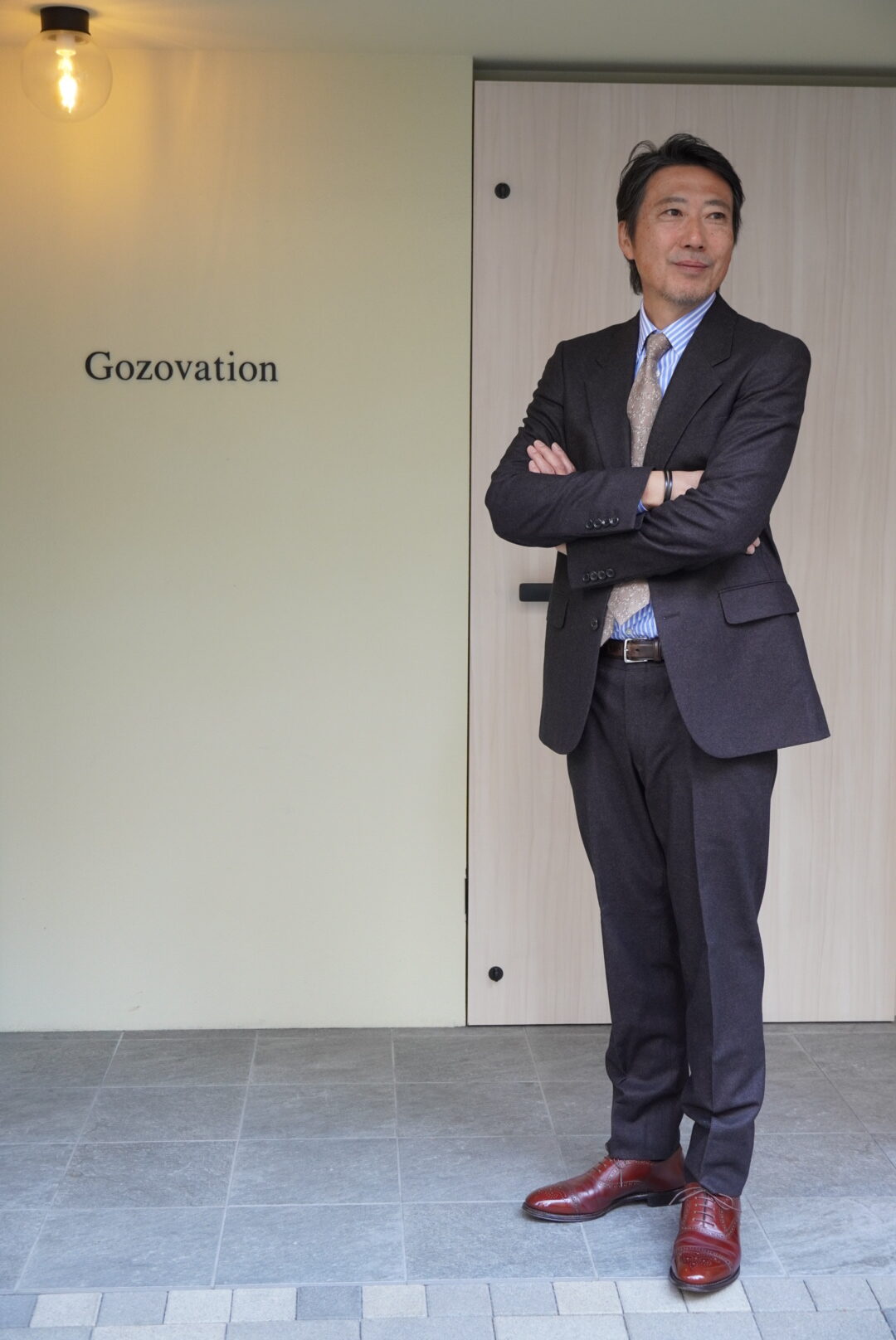 Gozovation前でバーガンディーのコードバン ES-06を履いているオーナーがダークブラウンのスーツ姿で立っている様子